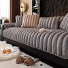 A gray thickened plush sofa seat cushion is displayed on a black sofa, with small faux fur items nearby.