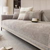 A light gray linen sofa cover with matching pillows and a white cup rests on a modern sofa.