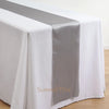 Elegant satin table runner in silver gray draped across a white tablecloth.