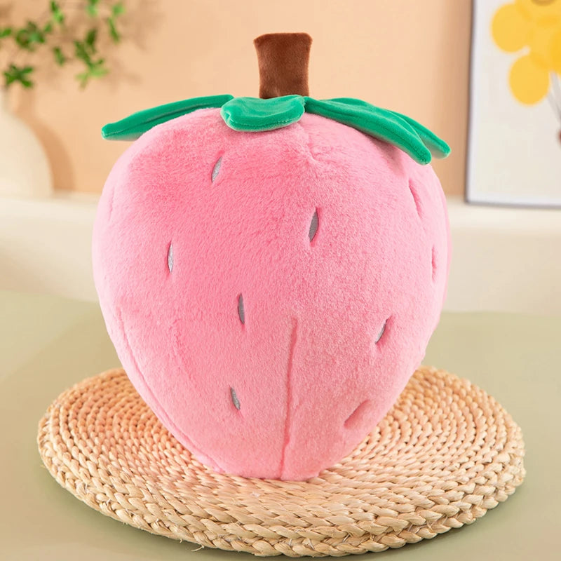 A pink plush strawberry throw pillow resting on a woven straw mat.