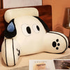 A white plush animal cushion with black ears and eyes resting on a wooden surface.