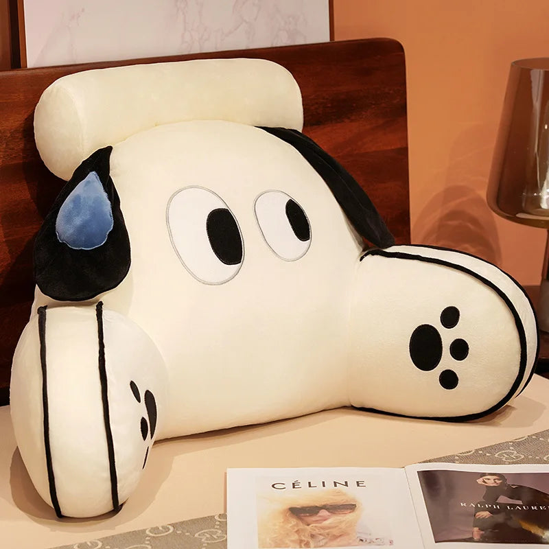 A white plush animal cushion with black ears and eyes resting on a wooden surface.