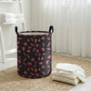 A black laundry basket with a pink leopard print pattern sitting on a beige rug near a window.