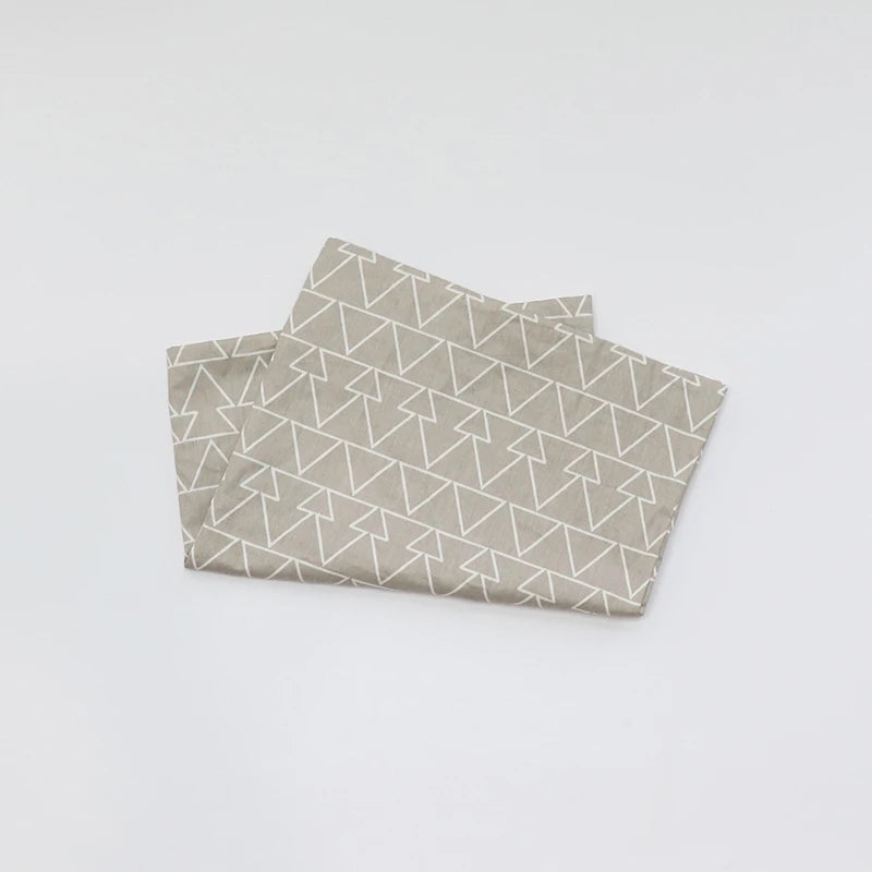 A folded soft cotton baby pillow cover with a geometric pattern on a white background.