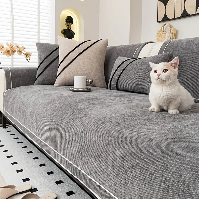 A gray chenille sofa protector cover is displayed on a sofa with striped pillows and a white cat.