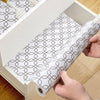 Hands are pulling a roll of silicone non-slip drawer liner out of a white storage box.