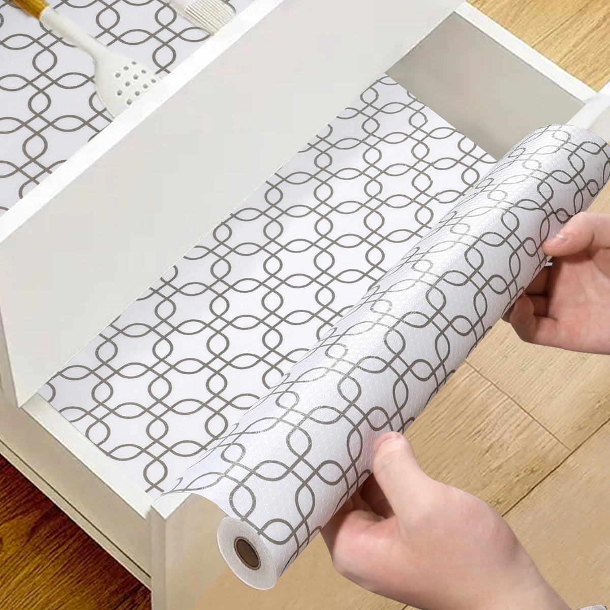 Hands are pulling a roll of silicone non-slip drawer liner out of a white storage box.