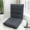 A dark gray folding tatami seat cover placed on a white floor, next to a potted cactus.