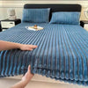 A close-up view of thick blue textured bed sheets on a bed with dark bedding and pillows.