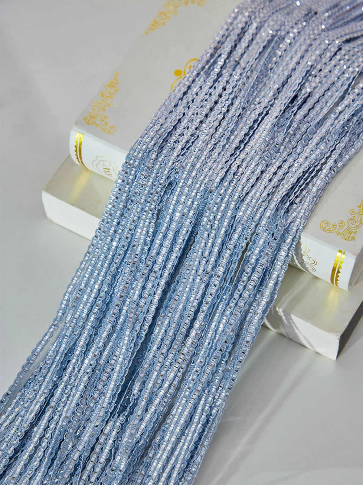 A close-up of blue decorative door string curtains hanging on a white wooden surface.