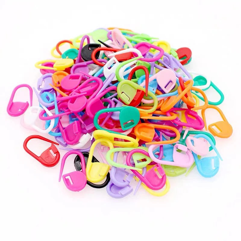 A pile of colorful plastic stitch markers for knitting and crochet in various bright colors.