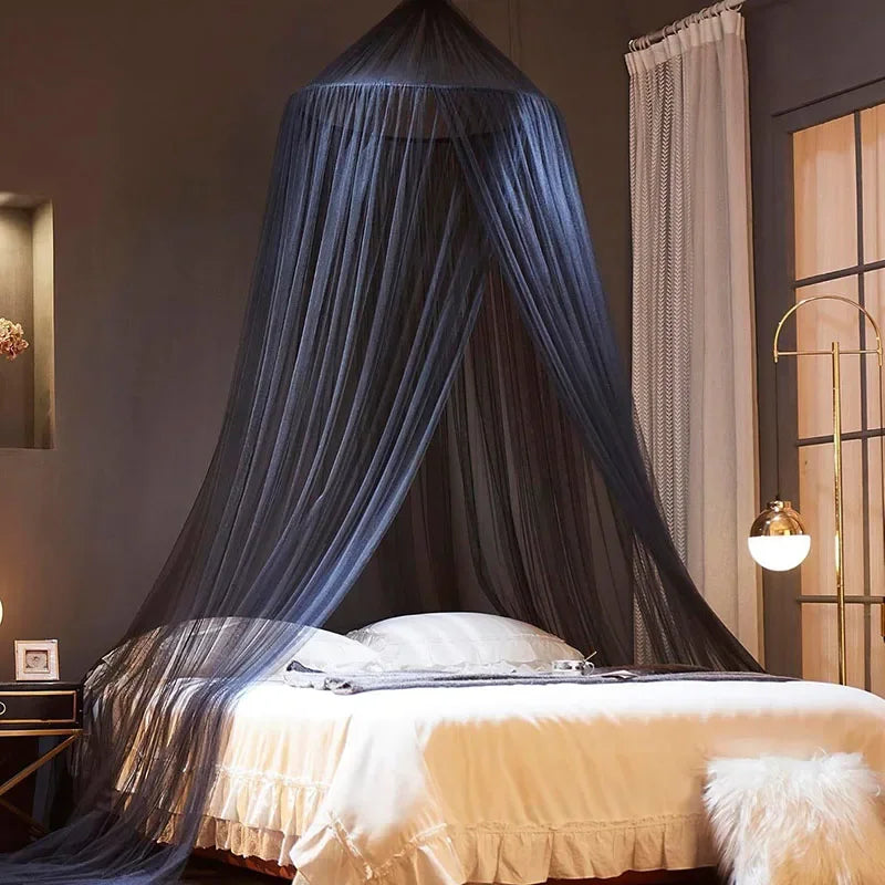 A floor-to-ceiling mosquito net canopy draped over a bed, featuring sheer blue fabric and white bedding.