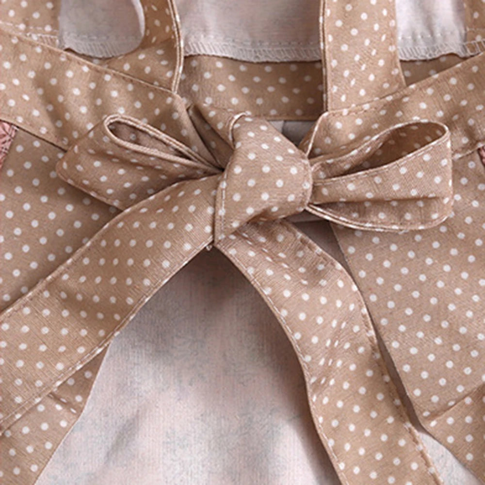 A beige floral patterned kitchen apron with adjustable straps tied in a bow.