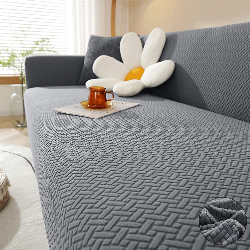 A gray jacquard sofa cover featuring a white, petal-shaped accent cushion with an orange mug on the fabric.