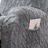 A close-up of a gray faux fur sofa cover featuring a textured, knitted pattern with a small card tucked into the fabric.