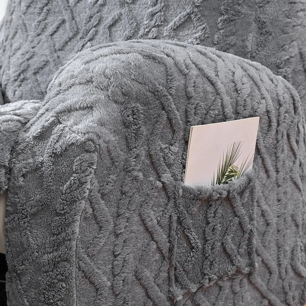 A close-up of a gray faux fur sofa cover featuring a textured, knitted pattern with a small card tucked into the fabric.
