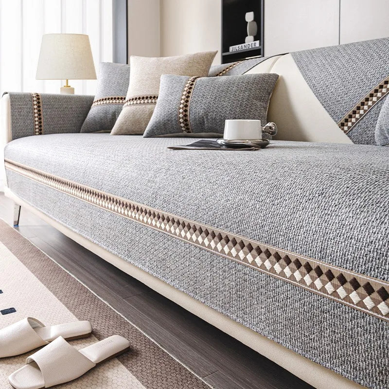 A light gray linen sofa cover with beige accent piping and pillows on a modern sofa.