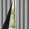 Solid black blackout privacy curtains hanging in a window frame.