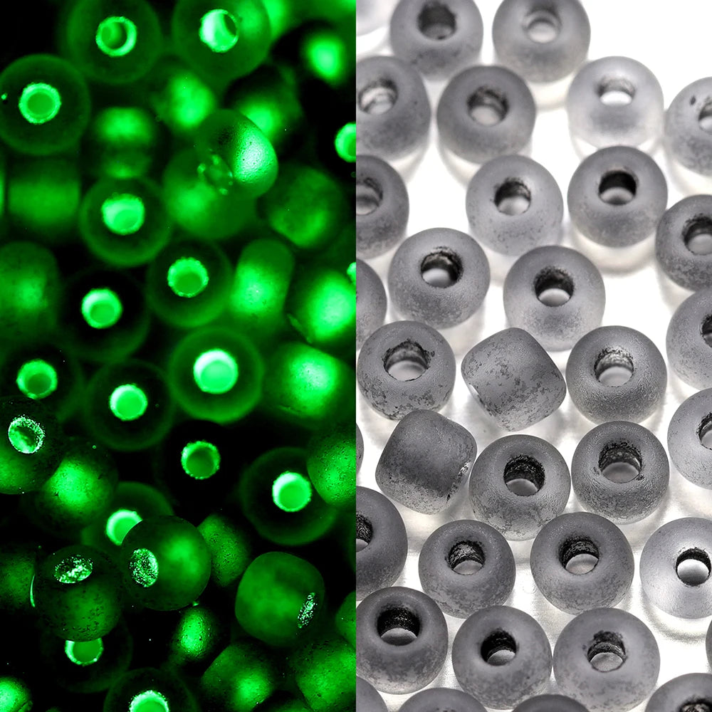 A close-up view of green glow-in-the-dark glass seed beads, some appearing bright green and others dark gray.