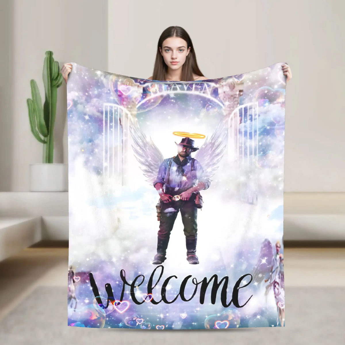 A person holds up a purple and white blanket featuring a winged figure in a hat surrounded by sparkling light.