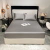 A luxury bed setup featuring a fitted sheet, pillows, and dark headboard in a modern bedroom setting.