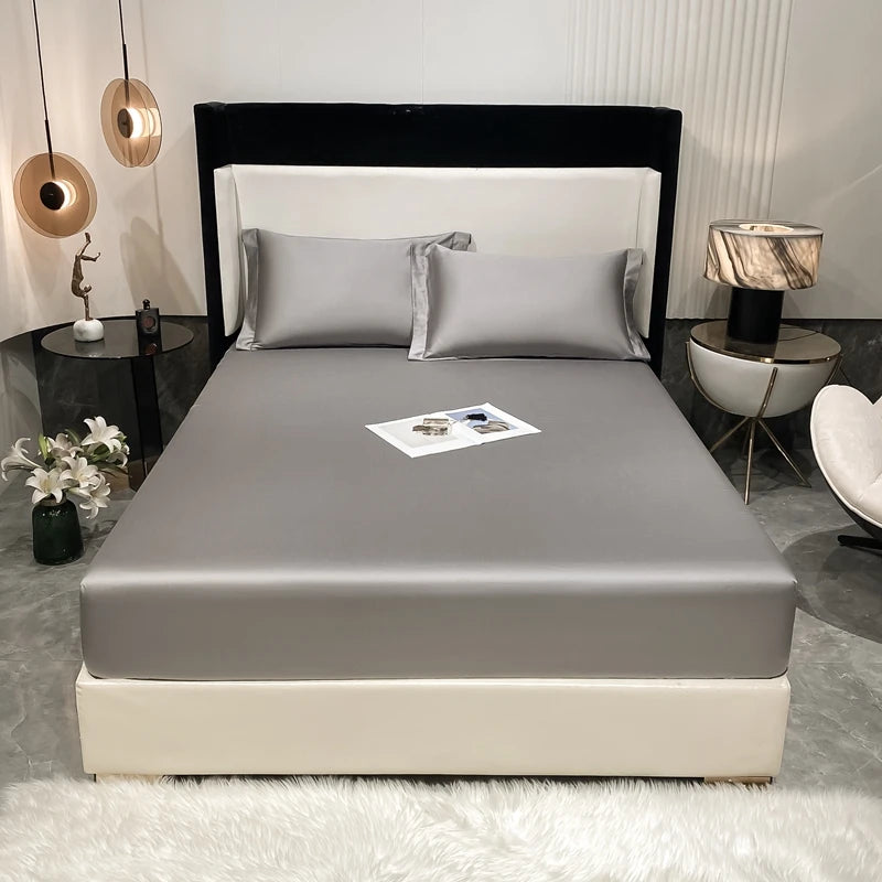 A luxury bed setup featuring a fitted sheet, pillows, and dark headboard in a modern bedroom setting.