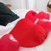 A close-up of several bright red memory foam contour chest pillows resting on white bedding.