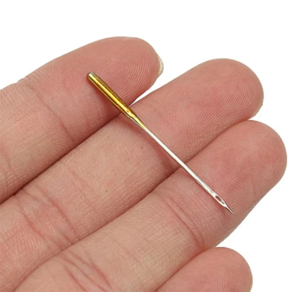 A hand holds a single gold-colored precision sewing needle.