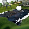 A black and white faux animal skin rug is placed on a green lawn with a white sphere nearby.