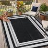 A black and white striped outdoor patio rug placed on a wooden deck with potted plants and a chair.