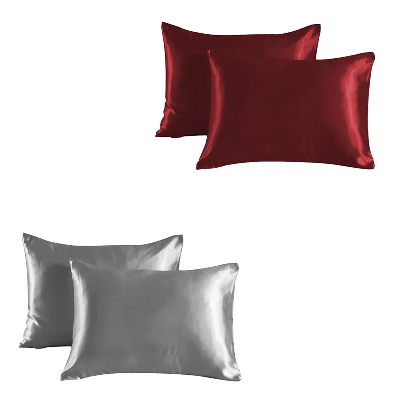 A set of two satin silk pillowcases, one in deep burgundy and one in silver gray.