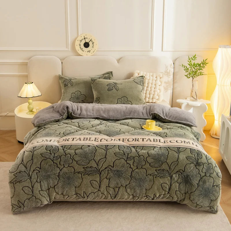 A thick, quilted lamb'swool winter blanket in sage green rests on a bed with light-colored linens and decorative pillows.