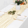 A white table setting featuring a beige boho gauze table runner, plates, silverware, and floral arrangement.