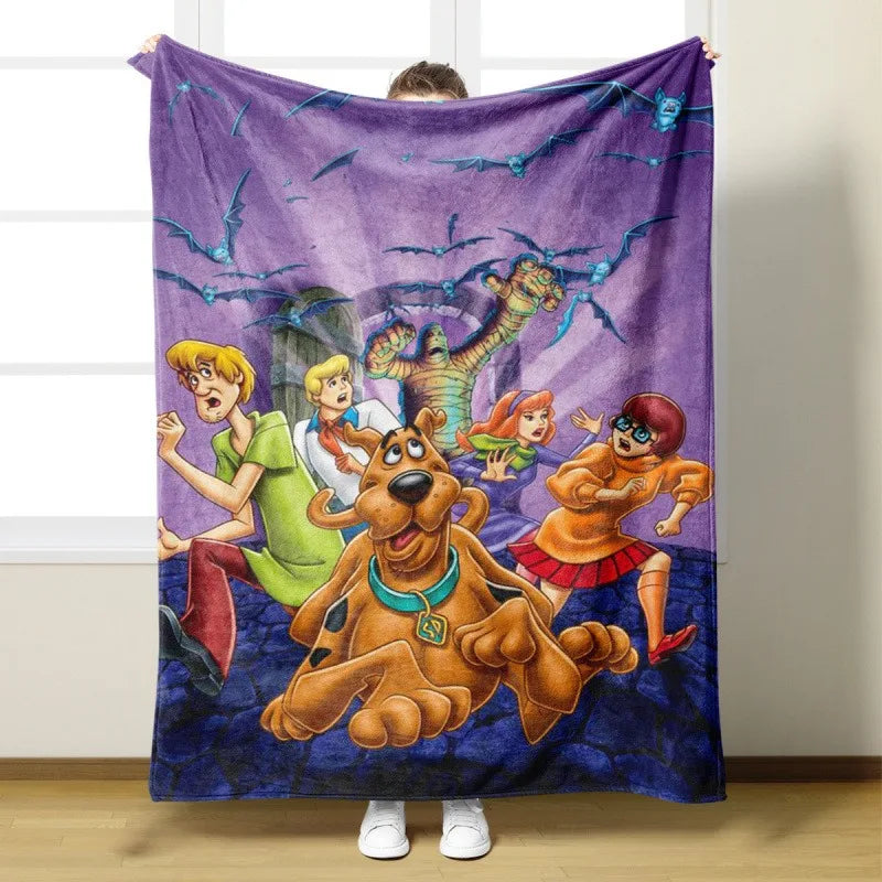 A purple flannel throw blanket featuring a cartoon illustration of Scooby-Doo and other characters.