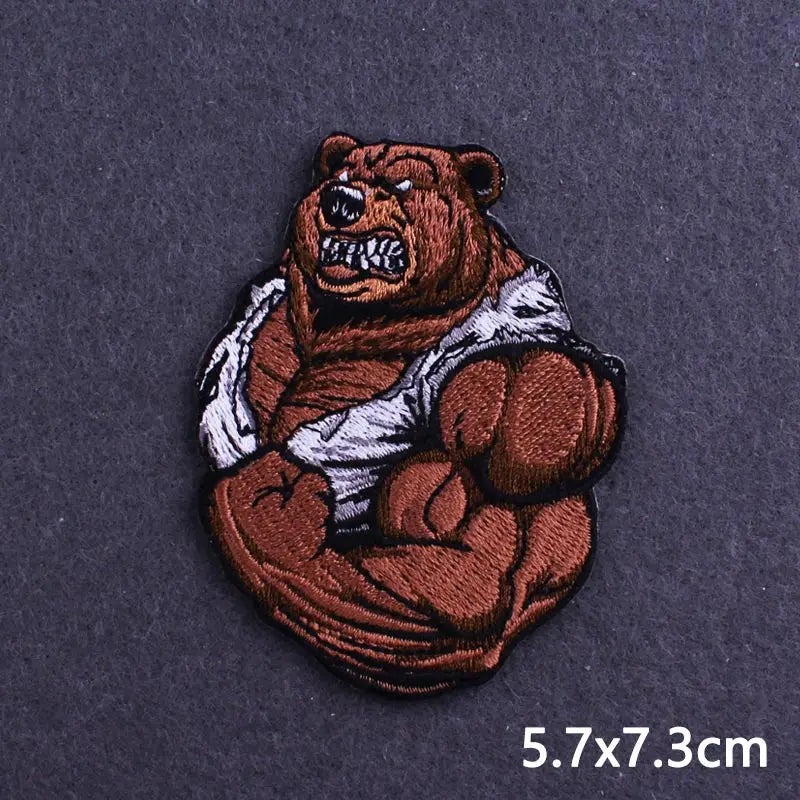A dark brown embroidered patch of a fierce bear head with white fur details on a dark gray fabric.