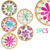 A set of five decorative woven shell coasters featuring floral patterns in various shades of green, pink, and purple.