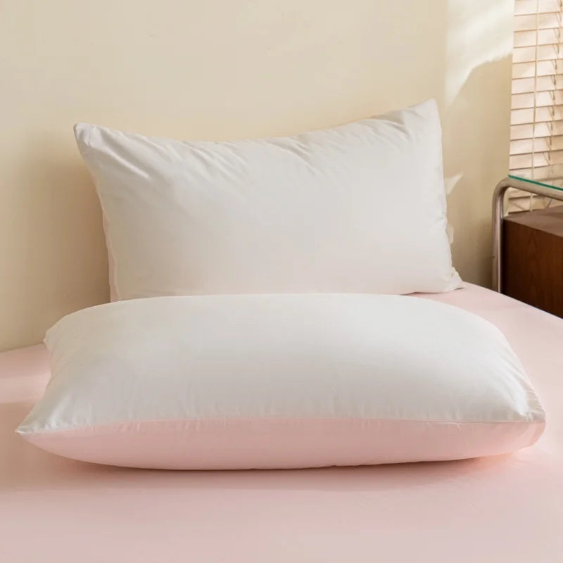 A set of three white and pink polyester bedding pillows resting on a pink bed.