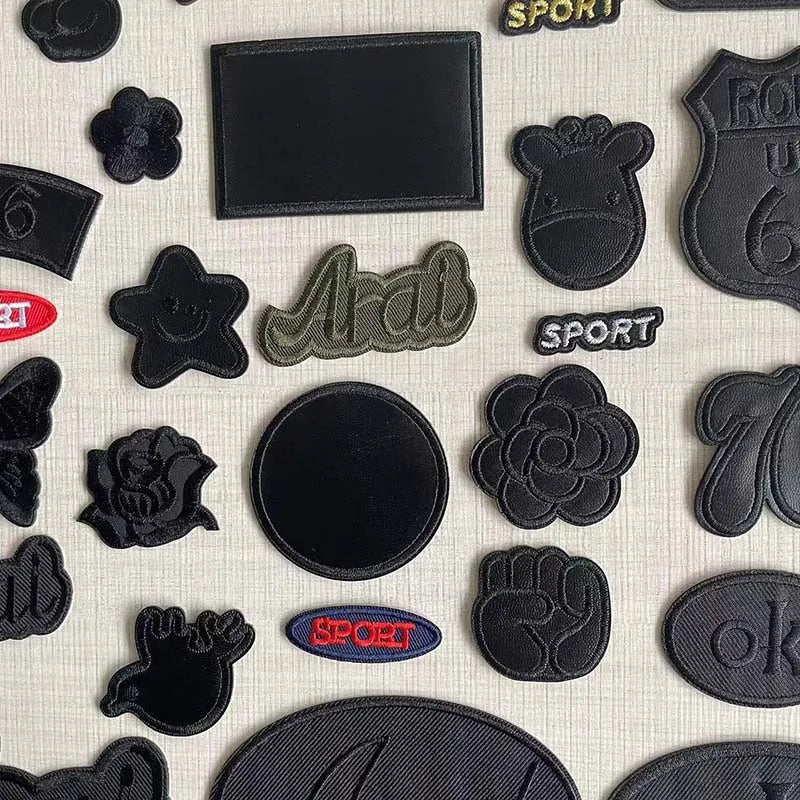 A collection of five black embroidered leather patches with self-adhesive backing, featuring various shapes and text like SPO