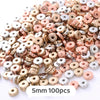 A pile of small, round geometric acrylic beads in various rose gold and silver colors for jewelry making