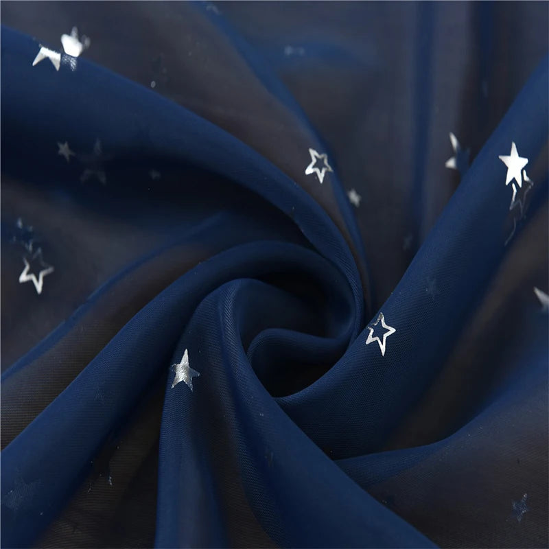 Dark blue tulle fabric with silver stars is draped and folded, showing elegant texture.