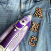 A purple and white iron-on patch featuring the letter A, B, and C in leopard print.
