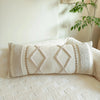 A close-up of a cream knit pillow cover with diamond stitching resting on a white sofa.