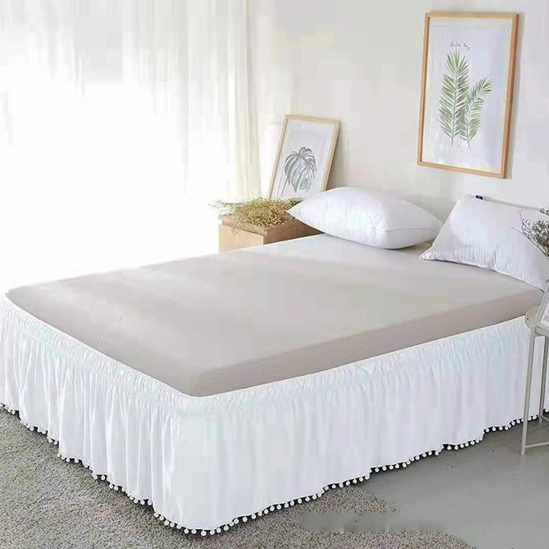 A white bed with an elegant elastic skirt and white bedding set in a bright room.
