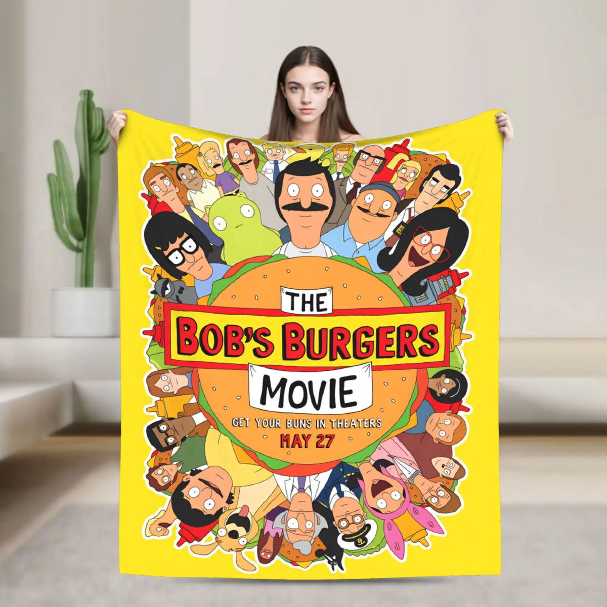 A yellow throw blanket featuring a graphic of characters from The Bob's Burgers movie poster.
