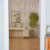 Decorative door string curtains in gold thread hanging in a white framed doorway.