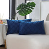 Two navy blue velvet decorative pillow covers resting on a white sofa.