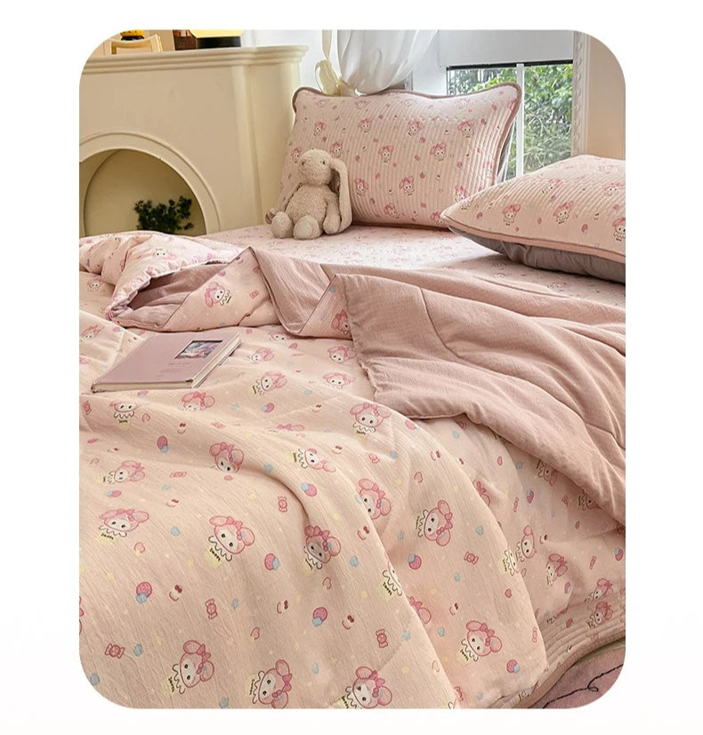 A pink cartoon quilting comforter with a floral pattern is displayed on a bed next to a light-colored headboard.