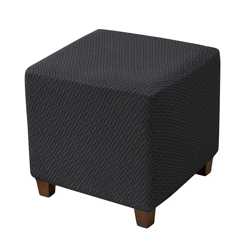 A dark gray woven fabric ottoman slipcover with wooden legs.