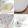 A white memory foam cushion with a geometric pattern and non-slip backing.