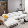 A modern beige sofa with white cushions and a gray rug in a living room setting.